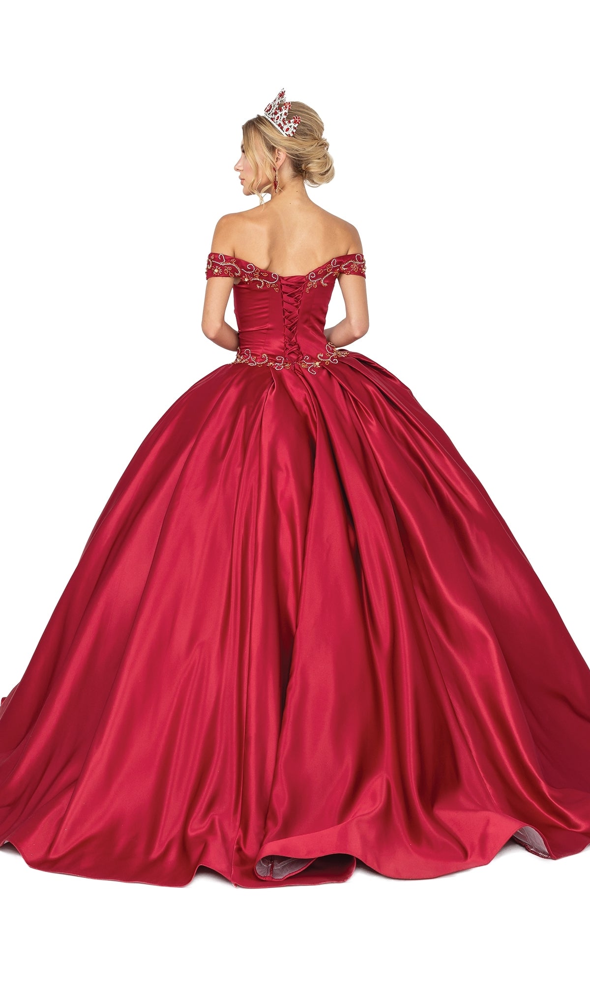 A woman stands with her back to the camera against a white background, wearing Quinceanera Dress 1466 by Dancing Queen—a red, off-the-shoulder, floor-length ball gown with a full skirt and a tiara.